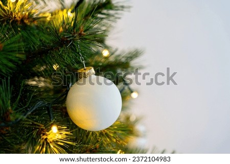 White bauble hanging on chistmas tree
