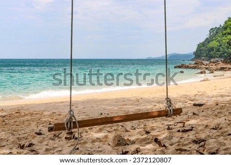 Homemade swing against the backdrop of a beautiful sea with azure water, a tropical island. Classic background for tourist advertising.