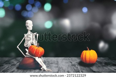 Halloween Party Card - Pumpkins And Skeleton In Graveyard At Night, Art Picture for Halloween Concept, copy space, funny skeleton sitting on wooden floor with pumpkin on lap. Isolated on black.