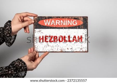 Hezbollah. Warning sign with text in the hands of a woman.