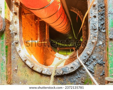 mud tank cleaning process. gas testing using a portable gas detector in front of the mainhole and also providing a portable hose blower fan on the tank to remove toxic gases Royalty-Free Stock Photo #2372135781
