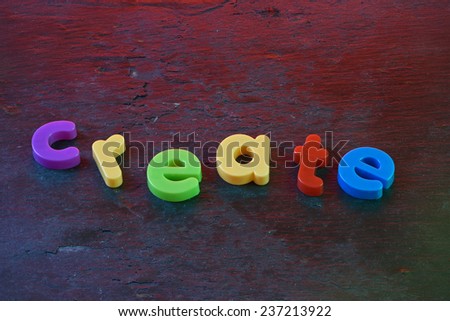 The word 'create,spelled out in colorful fridge magnets on a slate background