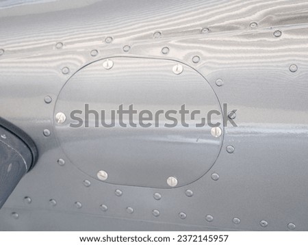 Screwed cover on plane body. Detail of smalll airplane body. Ultralight plane or drone,  aluminum cover with rivets. Airplane airframe close-up Royalty-Free Stock Photo #2372145957