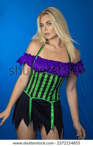 Young beautiful blonde woman in a witch costume on a blue background. Short dress, long hair. Halloween concept. Soft focus