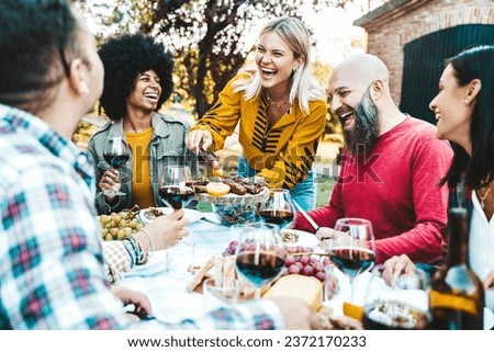 Happy friends having bbq dinner party at backyard -Multiracial young people eating food and drinking red wine in garden restaurant  Royalty-Free Stock Photo #2372170233