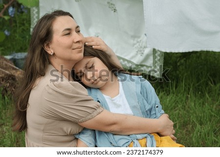 Amidst fluttering laundry, mother and daughter share joyous embrace in the backyard. moment highlights irreplaceable bond between parent and child, foundational to child's emotional development. Royalty-Free Stock Photo #2372174379