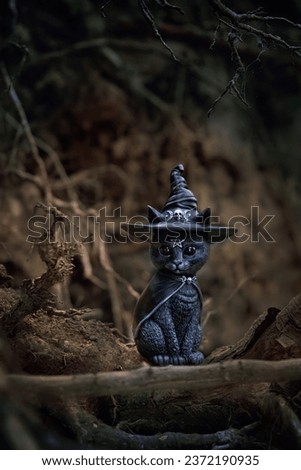 black witch cat figurine in forest, mystery autumn dark natural background. black cat - symbol of witchcraft, magic. samhain sabbat, Halloween holiday. fall season. template for design