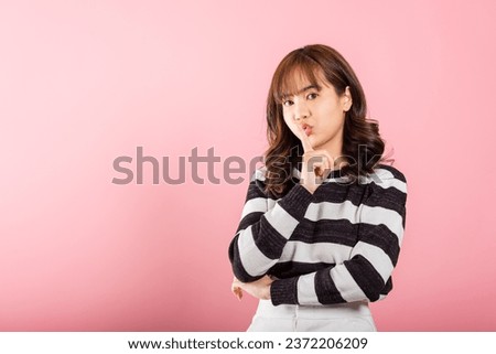 Woman making finger on lips mouth silent quiet gesture, Happy Asian beautiful young female marking silence for stop quiet, mute studio shot isolated on pink background with copy space