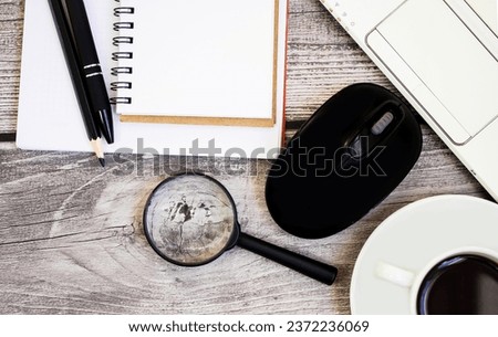 Close-up, flat lay on a wooden table laptop, white cup with coffee and magnifying glass magnifying glass, notepad, pen, computer mouse.  Financial economics concept, online training, webinars.