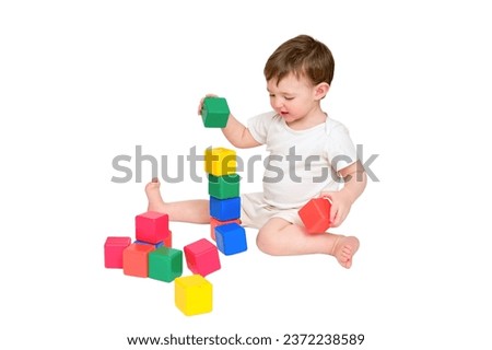 Happy baby play educational toys on studio, isolated on white background. Portrait of a smiling child playing while sitting on the floor, isolated on white background. Kid about two years old