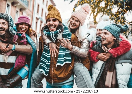 Happy group of friends wearing winter clothes having fun celebrating Christmas day together - Cheerful young people laughing together walking on city street - Winter holidays and friendship concept 