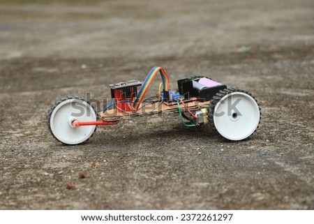 View of a robotic car having 3 wheels. Robot car that is controlled using a programmable micro controller board working prototype Royalty-Free Stock Photo #2372261297