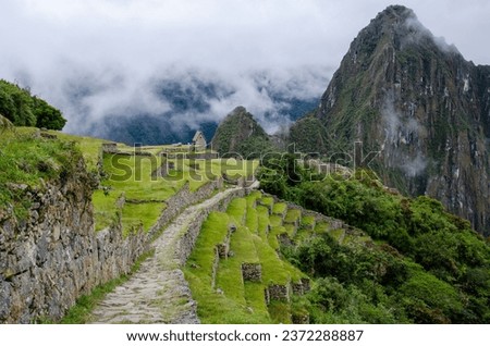 On the Inca Trail coming down from the Sun Gate (Inti Punku, elevation 2,745 m) to Machu Picchu, elevation 2,446 m. The caretaker's hut in the background marks the entrance to the Inca citadel below. Royalty-Free Stock Photo #2372288887