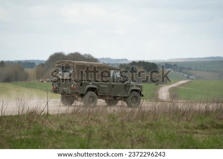 Army Land Rover Wolf Defender with canvass back cover driving on a dirt road Royalty-Free Stock Photo #2372296243