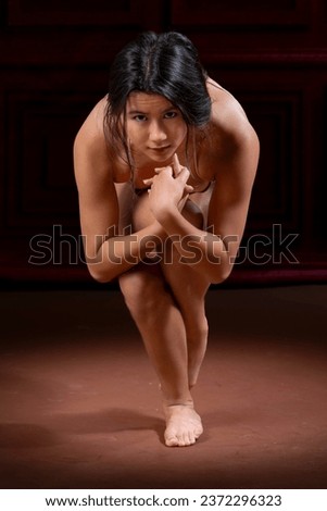 teen girl stretching in a studio with knees up and arms above her head