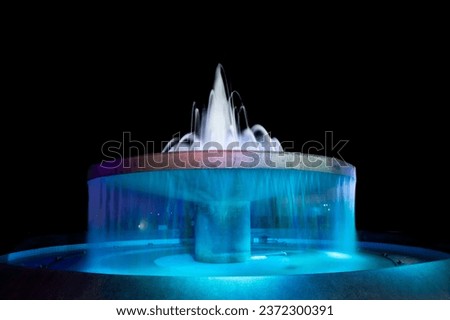 Fountain bath decorates the garden beautifully at night.Fountain with colored lights in celebration on black background. Royalty-Free Stock Photo #2372300391