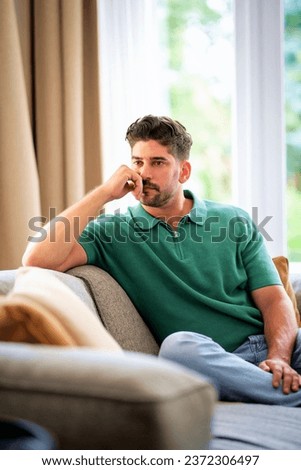 Portrait of a thinking man relaxing on the sofa at home. Mid aged man wearing casual clothes.  Royalty-Free Stock Photo #2372306497
