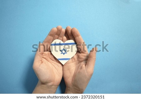 The concept of ending the war in Israel. heart in the colors of the flag of Israel in female hands Royalty-Free Stock Photo #2372320151