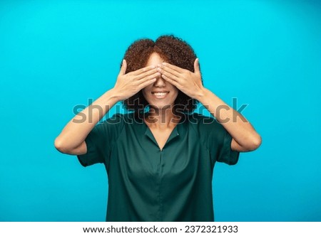 Young African American woman closed her eyes with her palms and smiles friendly standing isolated on blue color background