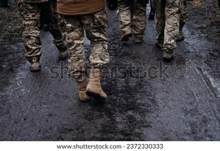 Men in military uniform walk down the road after the rain. Soldiers return home. Dramatic background, cold colors. Concept of war and peace, conflict between Ukraine and Russia. Royalty-Free Stock Photo #2372330333