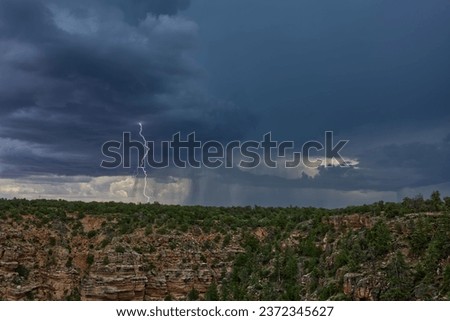 An Arizona Monsoon storm approaching Grand Canyon South Rim. This lightning strike was captured near the Desert View Point viewed from Navajo Point. Royalty-Free Stock Photo #2372345627