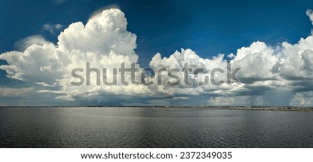 White fluffy cumulonimbus clouds forming from evaporating humidity of ocean water before thunderstorm on summer blue sky. Changing stormy cloudscape weather Royalty-Free Stock Photo #2372349035
