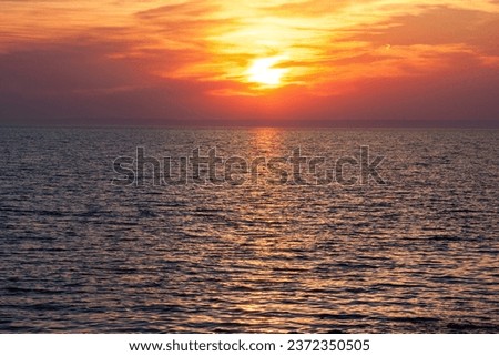 Sunset on the sea water with yellow, orange and red clouds