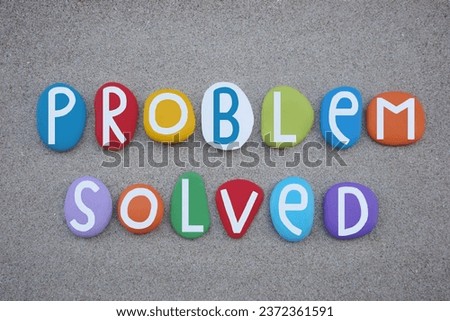 Problem solved, creative text composed with multi colored stone letters over beach sand