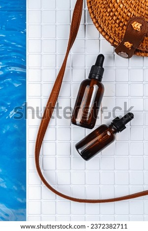 Body oil, orchid,  beach woven bag on a pool background. Body care product after the pool. Body lotion mockup with SPF. Cocktail by the pool. Safe tanning oil for body. 