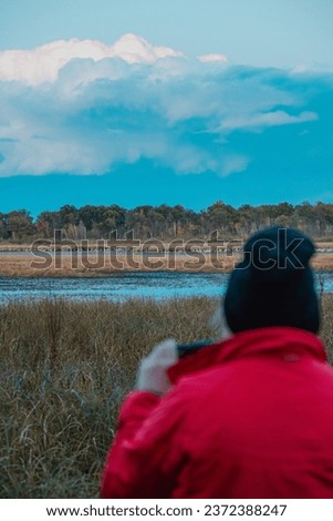 a woman taking pictures of sandhill cranes at the navarino nature center