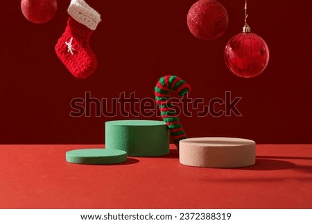 Front view of green and brown podiums decorated with cute red baubles and stock on red background. Space for cosmetic product mockup. Product and promotion concept for advertising