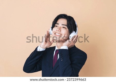 Young Asian businessman listing music with wireless headphones.