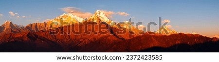 
A breathtaking panoramic shot captures the stunning Annapurna ranges and the iconic Mt. Machapuchare bathed in a warm red hue as seen from the vantage point of Poon Hill, Ghorepani, Nepal. 