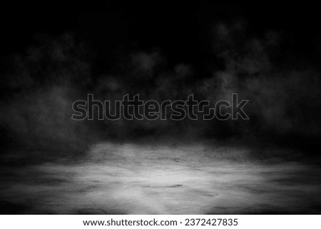 Concrete floor with smoke or fog in dark room with spotlight. Asphalt night street, black background, black and white
