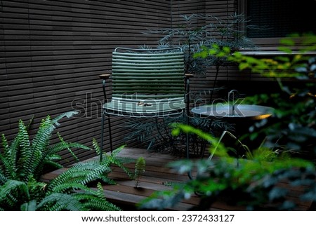 Real photo of a modern garden chair with table on a wooden deck in the garden of a weekend retreat