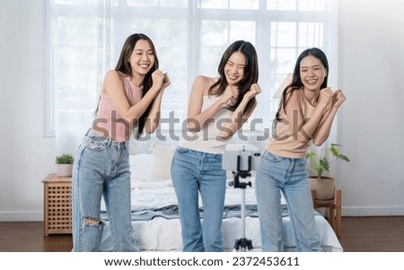 Young asian female influencer girl group record video on smartphone, dancing on camera at bed room home. Positive lifestyle vlog make content for blog, filming for social mediaAsian young woman Royalty-Free Stock Photo #2372453611
