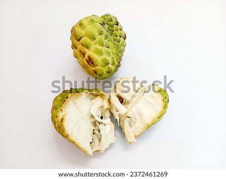 Thai fruit, picture of cut custard apple halves green outer surface Inside, the flesh is white and fluffy with black seeds. Custard apple flesh is fragrant. The taste is sweet and very delicious.