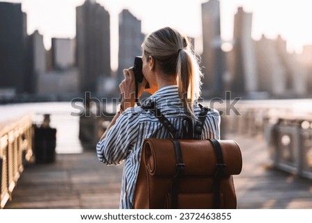 female tourist with trendy rucksack testing modern technology for making view photos
