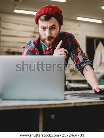 Craftsman in casual outfit browsing laptop at workshop