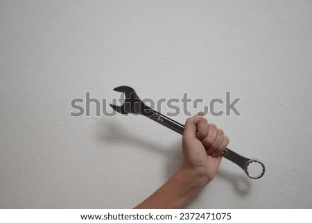 Human hand holding a wrench isolated on white background. Closeup. High resolution product. The mechanic's hand holds a wrench behind himself. Mechanic holding wrench for car repair
