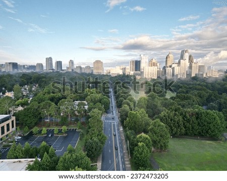 An Aerial view of green park with Atlanta skyline in the distance under dramatic sky