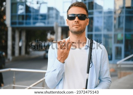 Young blinded man using phone and sending voice message. Royalty-Free Stock Photo #2372475143