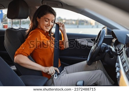 Young woman sitting on car seat and fastening seat belt, car safety concept. Woman fastens a seat belt in the car. Caucasian woman driver fastening car seat belt while sitting behind the wheel. Royalty-Free Stock Photo #2372488715