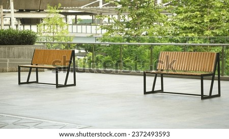 Modern outdoor setting with two wooden benches in an urban environment, complemented by greenery.