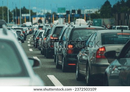 Large queue of vehicles on motorway pay toll in summer, selective focus Royalty-Free Stock Photo #2372503109