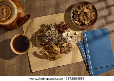 Top view of medicine cup, medicine package and dried herbs decorated on wooden table background. Collection of herbs to prepare a tonic drink, traditional medicine from China. Advertising photo Royalty-Free Stock Photo #2372504595
