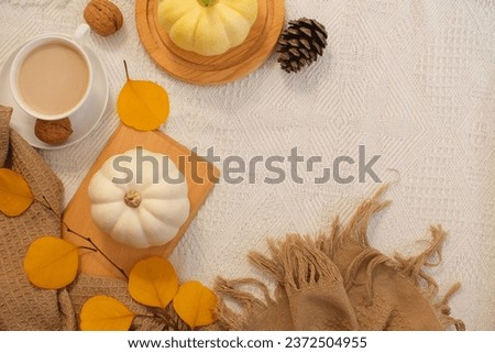 Creative autumn decoration concept with pumpkins, colorful dry leaves and hot coffee cups on vintage fabric background. Simple and warm color tones. Space for text and design. Advertising photo