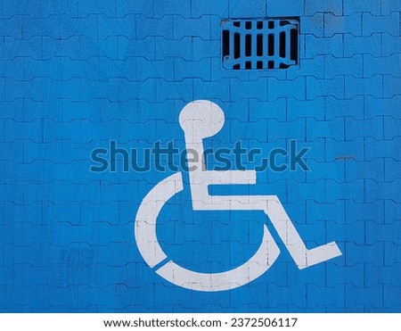 Road marking sign on a blue background denoting parking for a disabled vehicle. The convenience of parking a vehicle. The journey of people with disabilities in a wheelchair. Free space for the needy.