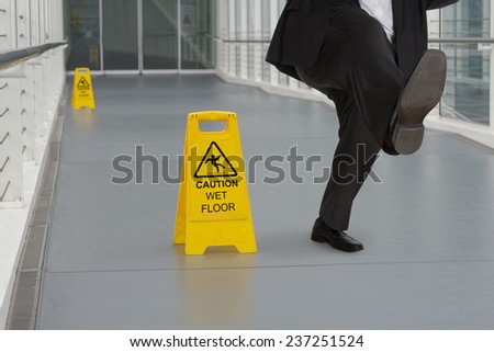 Man in suit slipping on wet floor with several warning signs