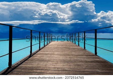 Close-up of a wooden pier (diminishing perspective) against a beautiful turquoise seascape and sky with storm clouds (cumulonimbus) and torrential rain.